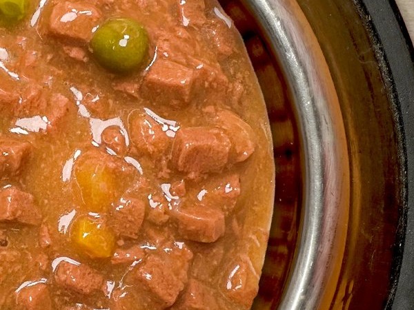 Churu Meal in Gravy served in a steel dog bowl: chunks of chicken with peas and carrot in gravy
