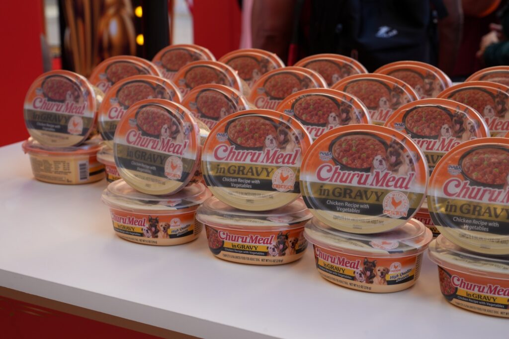 Rows of INABA Churu Meal in Gravy cups, Chicken Recipe with Vegetables, stacked on a table at INABA's Hollywood red carpet event